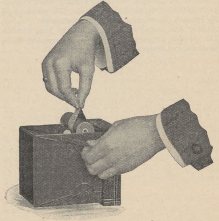 Hands lifting the exposed film reel from the opened roll holder.